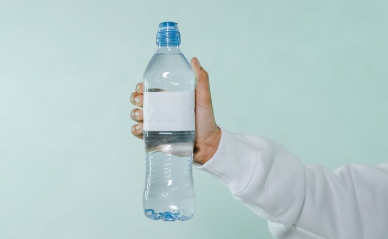 Photo of a Person's Hand Holding a Bottle of Water